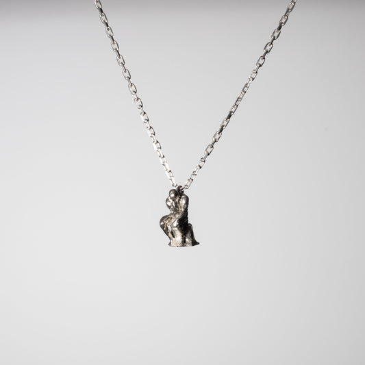 Product picture of a Sterling 925 silver pendant modeled after Rodin's sculpture 'The Thinker,' hanging from a silver chain. The pendant features a small, detailed rendition of the seated figure in a contemplative pose, captured against a minimalist white background, highlighting the craftsmanship and artistic design.