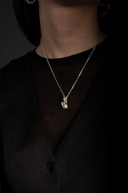 Sterling 925 silver pendant modeled after Rodin's sculpture 'The Thinker,' hanging from a delicate chain around the neck of the wearer, who is dressed in a black top. The pendant, depicting the seated figure in a contemplative pose, stands out against the dark background.